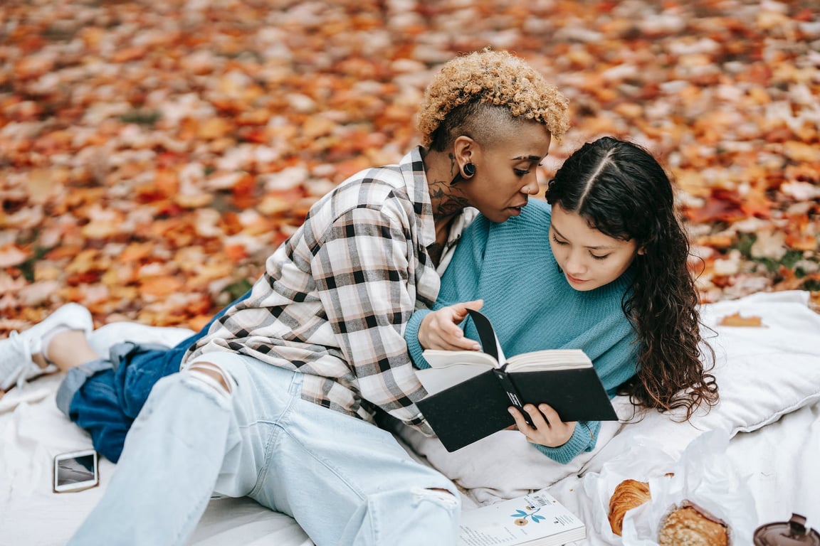 lesbiennes multiethniques aimant avec un livre dans un parc